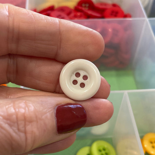 Hand holding a white button with a colorful array of buttons in the background