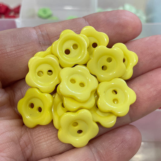Hand holding yellow flower-shaped buttons with a blurred background