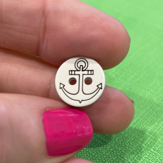 Small round metal object held between fingers against a green fabric background
