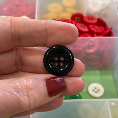 Hand holding a black button with a display of colorful buttons in the background