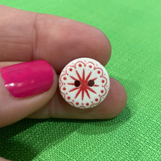 Small decorative button held between fingers against a green fabric background