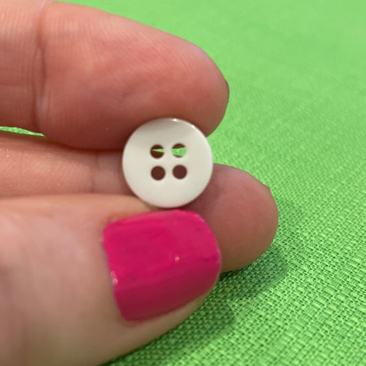 White button held between fingers against a green background