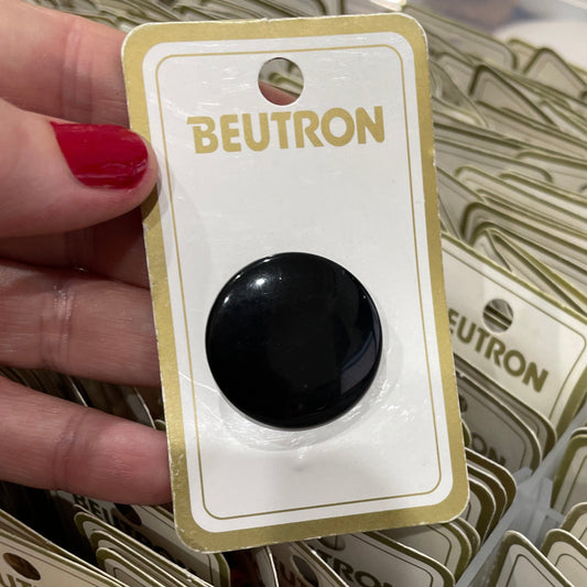 Hand holding a BEUTRON branded card with a black button, surrounded by similar cards.