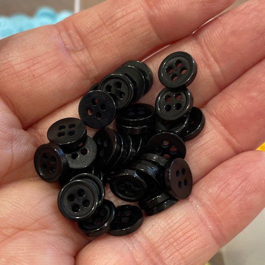 Hand holding a small pile of black buttons with a blurred background
