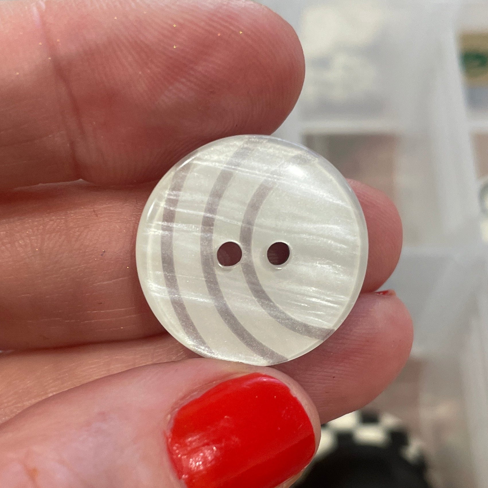Hand holding a button with a blurred background of button collection