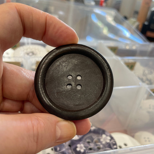 Hand holding a black button with a blurred background