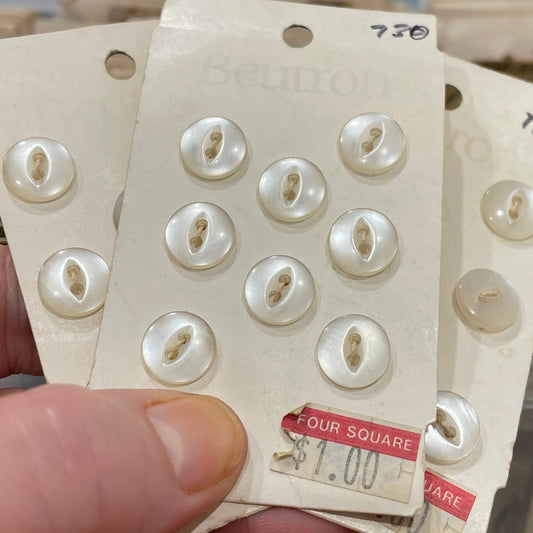 Hand holding a card with white buttons against a blurred background