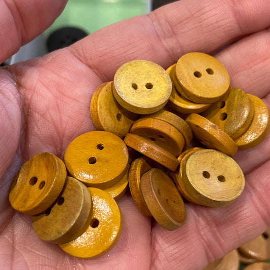 Hand holding yellow buttons with a container of buttons in the background