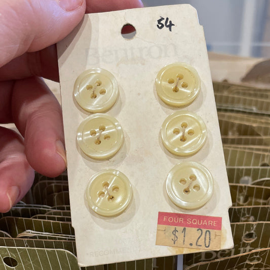 Hand holding a card with yellow buttons in front of a container.