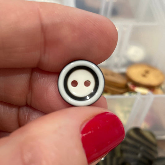 Small round button held between fingers with a blurred background