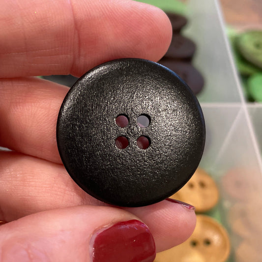 Person holding a black button with a collection of buttons in the background