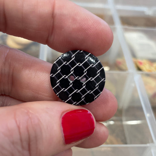 Hand holding a black and white patterned object with a blurred background