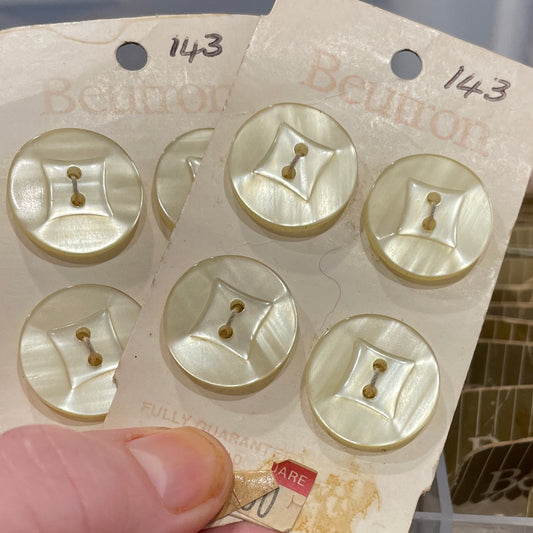 Hand holding a card with gold buttons against a blurred background