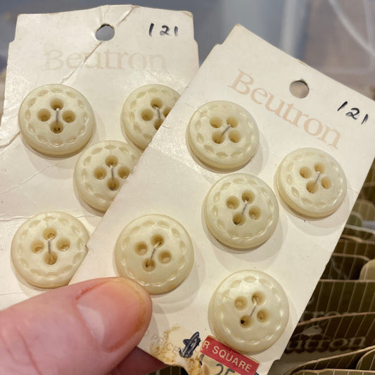 Hand holding a package of white buttons with a blurred background
