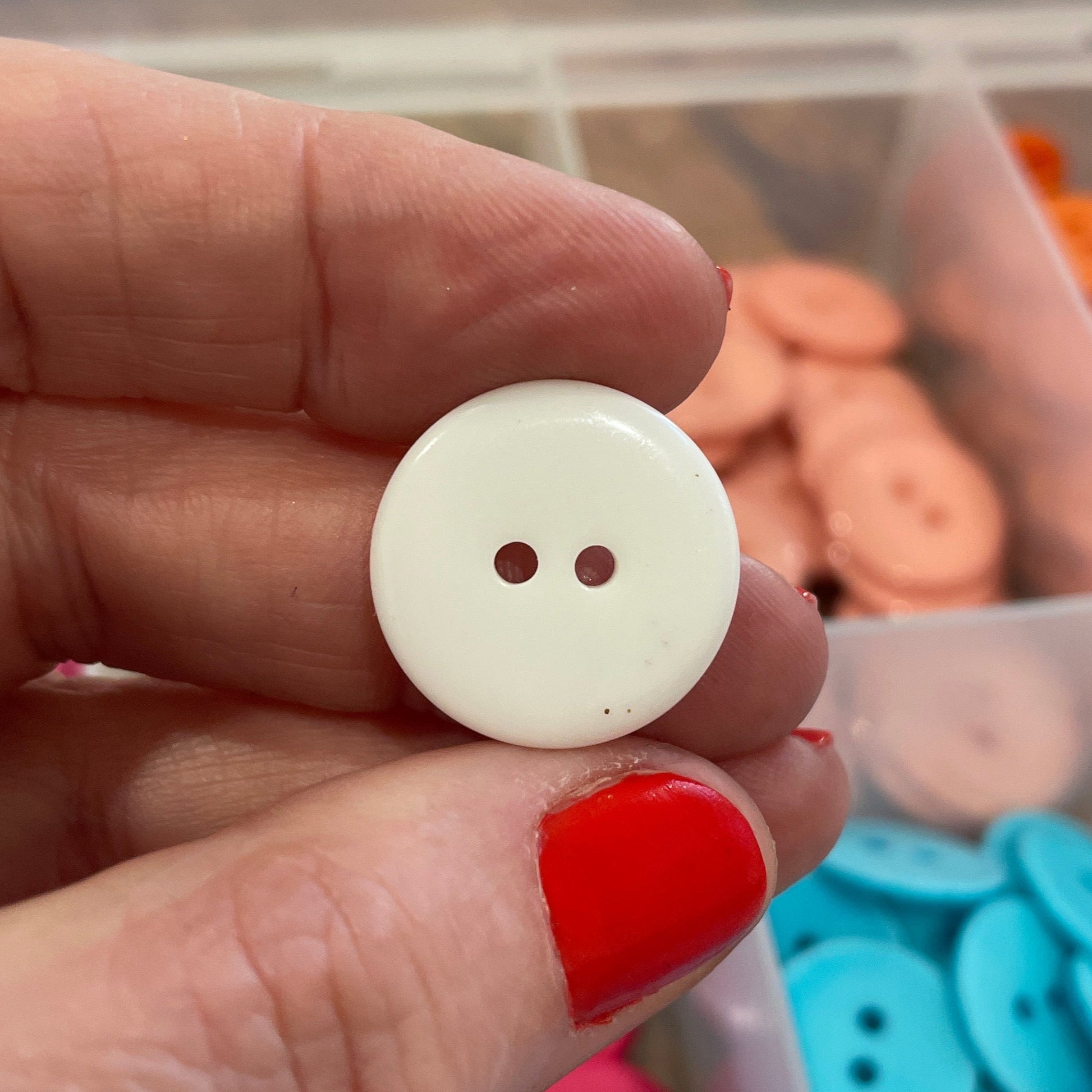 Hand holding a white button with colorful buttons in the background
