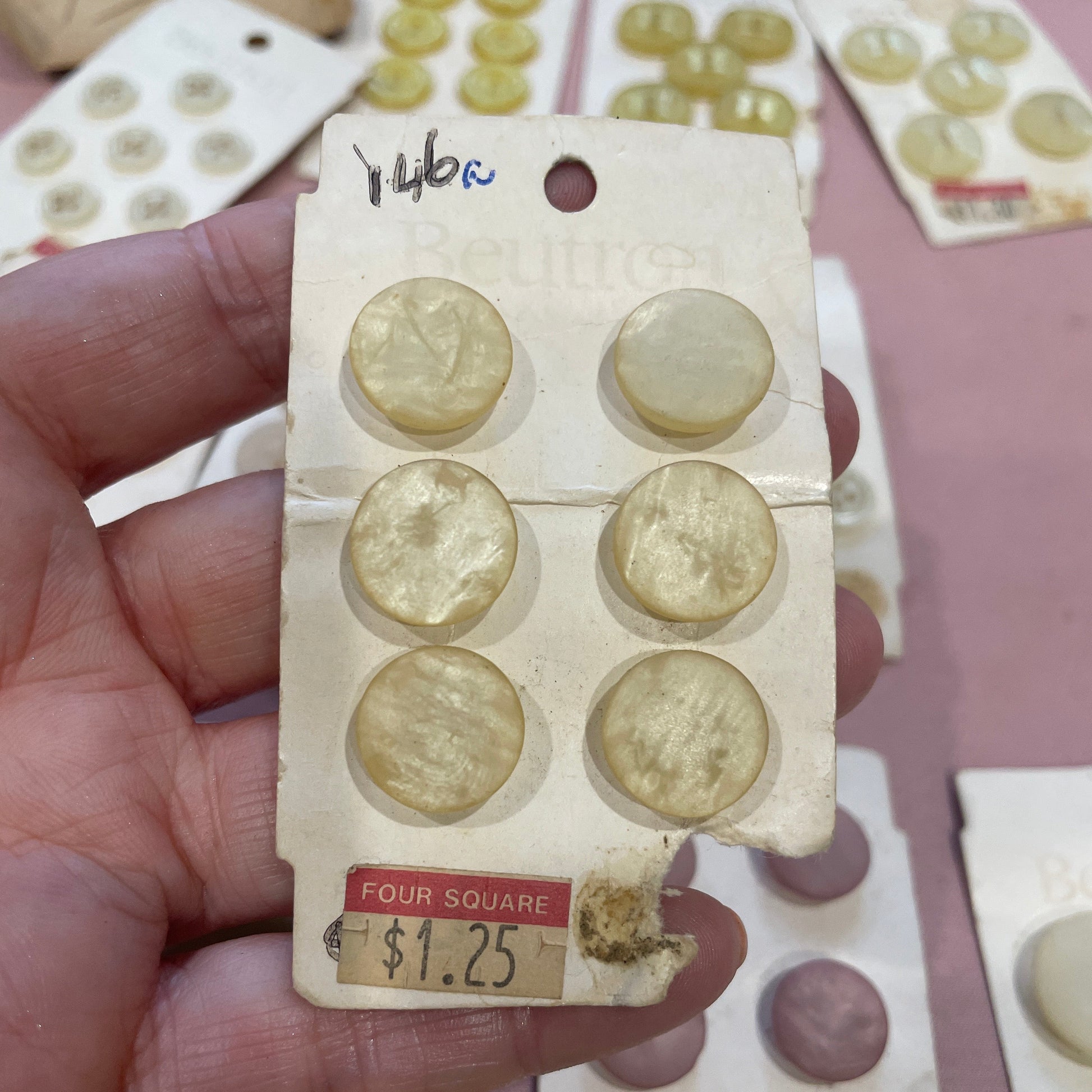 Collection of vintage buttons on a card held by a hand with a blurred background