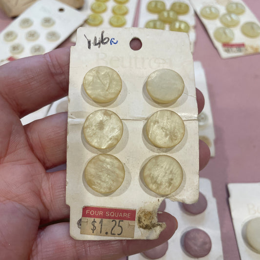Collection of vintage buttons on a card held by a hand with a blurred background
