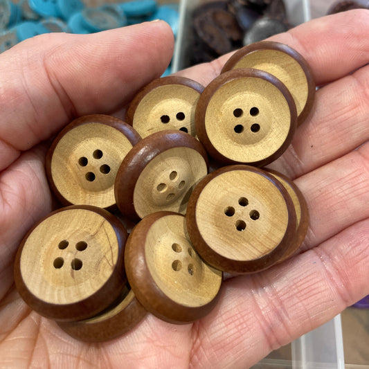 Hand holding six wooden buttons with a blurred background