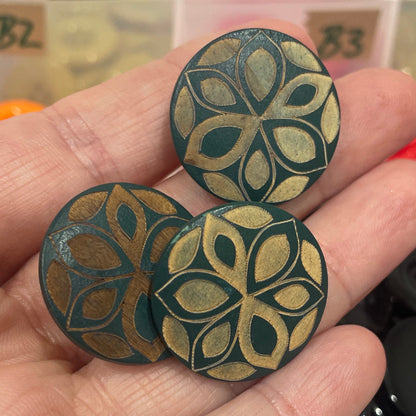 Hand holding decorative buttons with a button collection container in the background