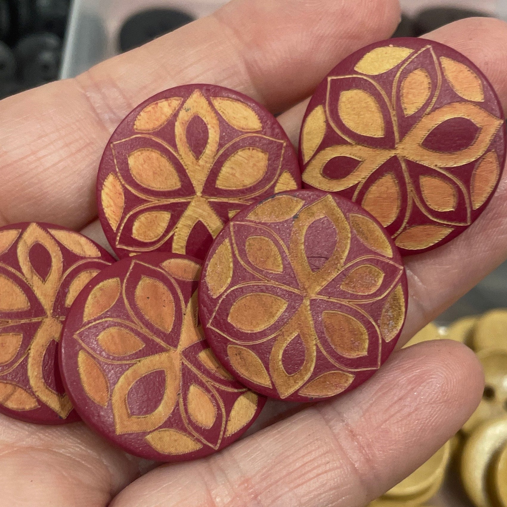 Hand holding decorative buttons with a background of button assortment