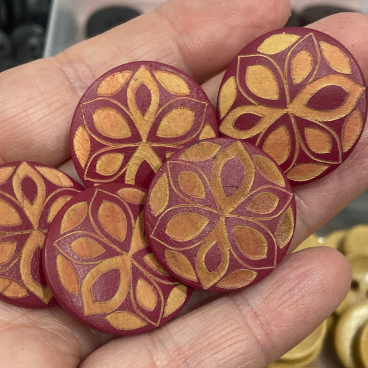 Hand holding decorative buttons with a background of button assortment