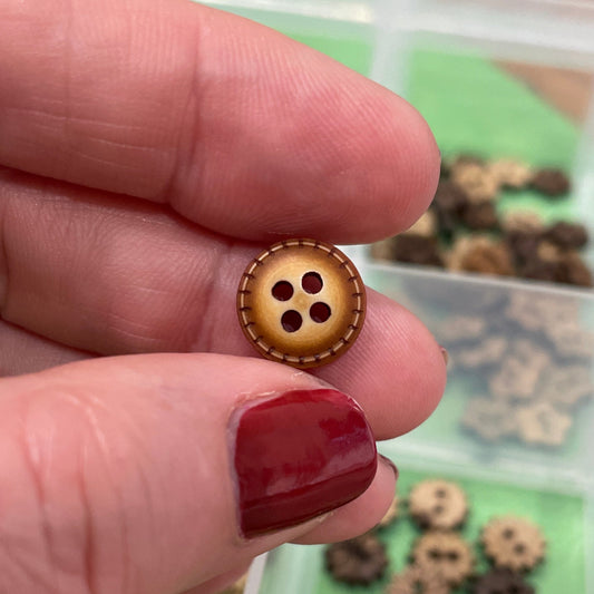 Hand holding a button with a clear container of buttons in the background