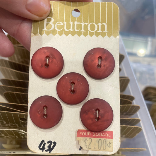 Card with red buttons held by a hand, with a blurred background of more buttons.