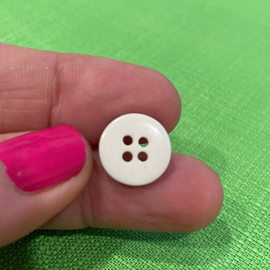 White button held between fingers against a green background