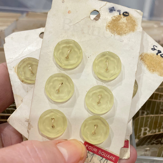 Hand holding a sheet of vintage buttons with a blurred background