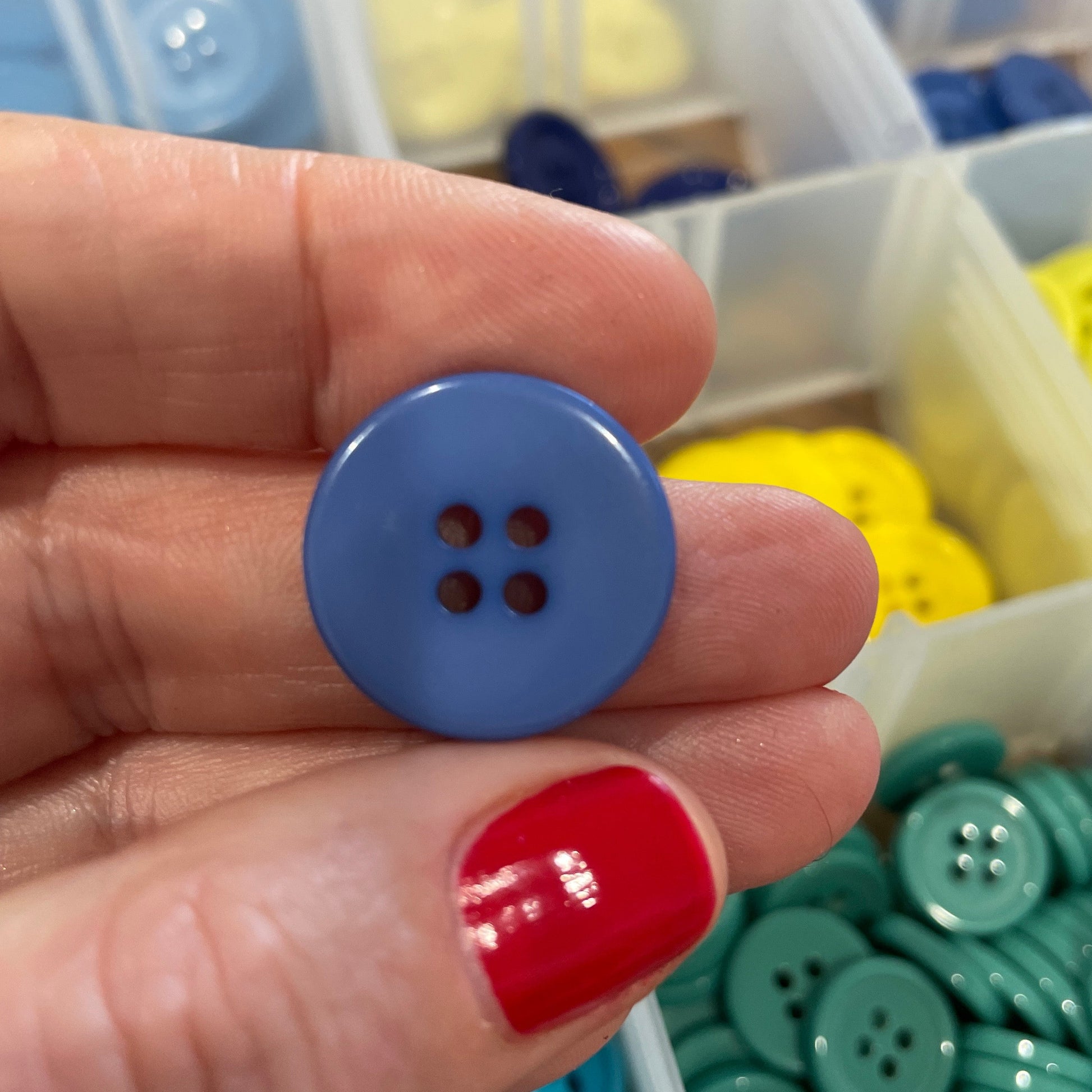 Hand holding a blue button with colorful buttons in the background