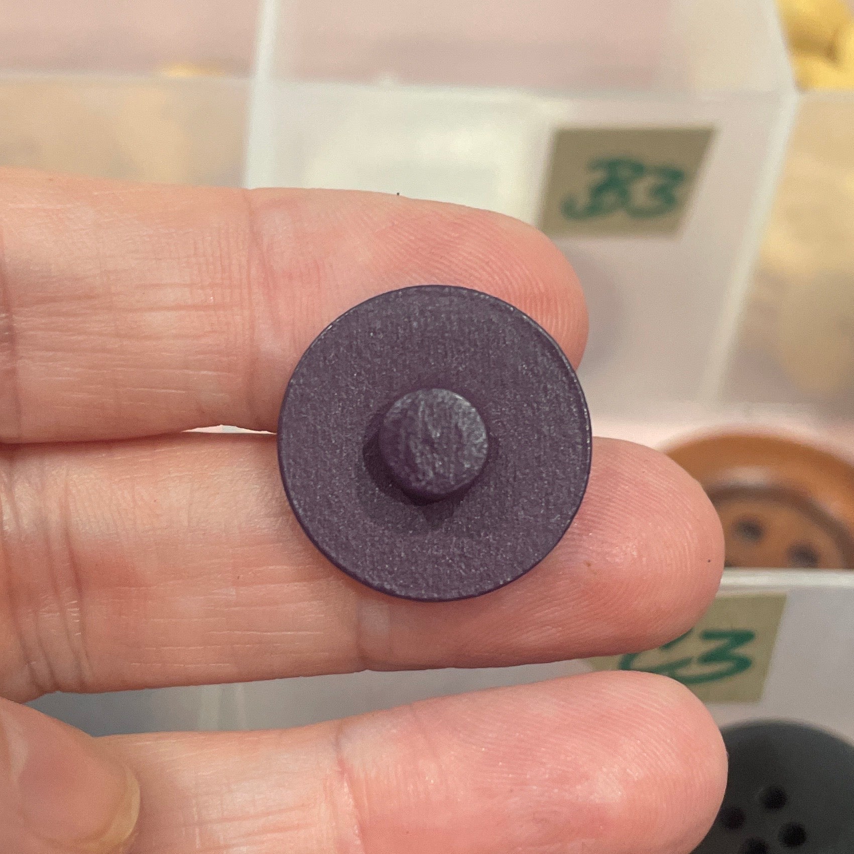Purple button held between fingers with a background of various buttons