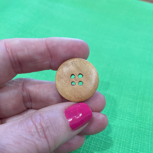 Hand holding a wooden button with a green background