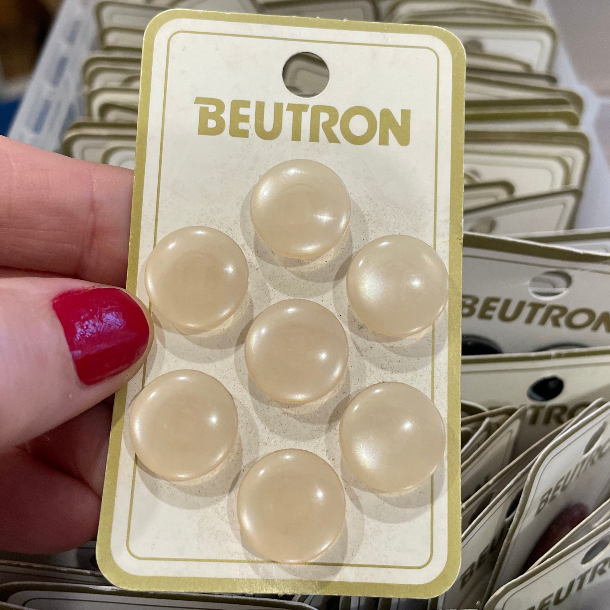 Hand holding a Beutron product packaging with multiple packages in the background.