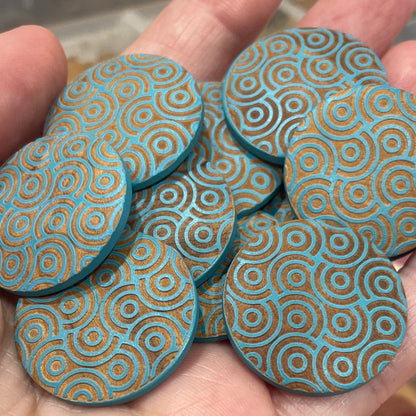 Hand holding blue patterned buttons with a container of similar items in the background