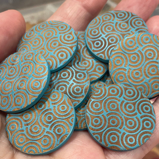 Hand holding blue patterned buttons with a container of similar items in the background