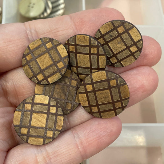 Hand holding decorative buttons with a clear container of various buttons in the background