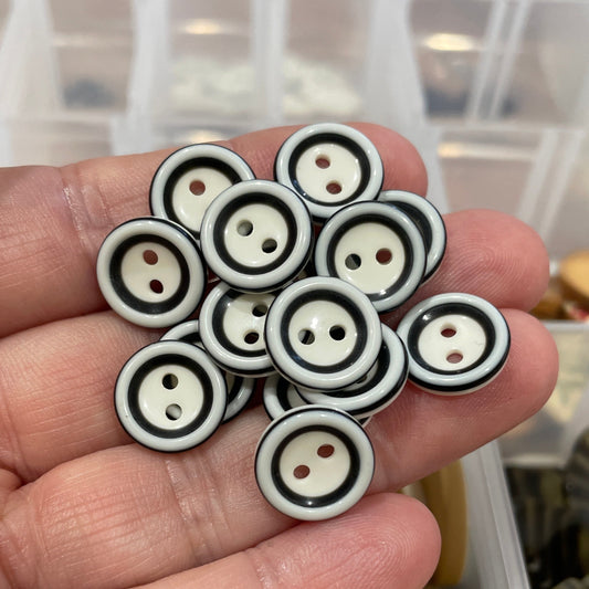 Hand holding a collection of black and white circular buttons with a blurred background