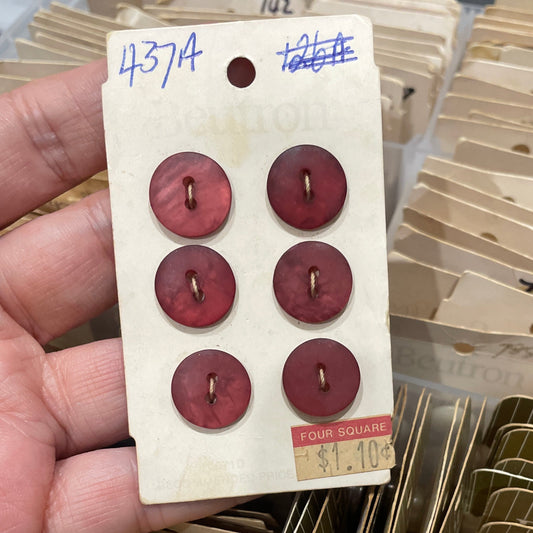 Card with red buttons held by a hand, with a container of similar cards in the background.