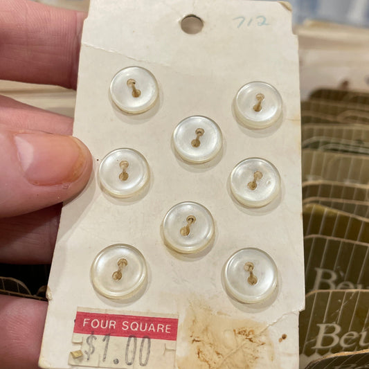 Card with pearl buttons held by a hand, with a blurred background