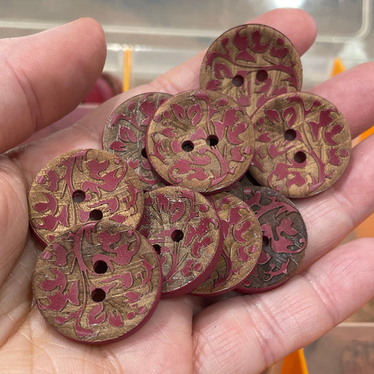 Hand holding decorative buttons with a background of button containers.