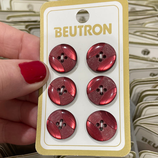 Card with red buttons held by a hand against a background of similar cards.