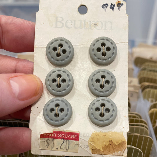 Set of gray buttons on a card held by a hand with a blurred background