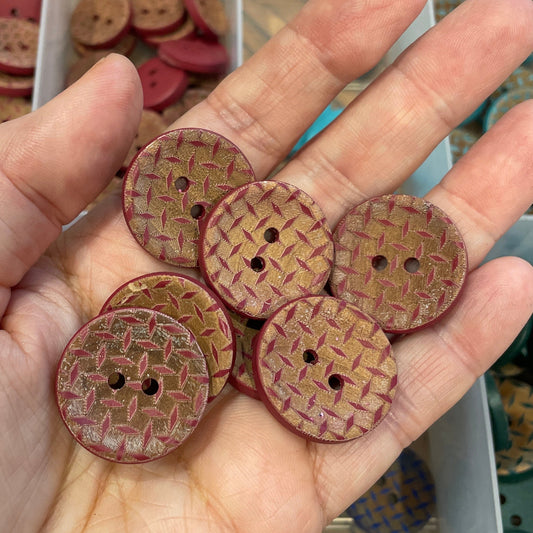 Hand holding wooden buttons with a clear container of buttons in the background