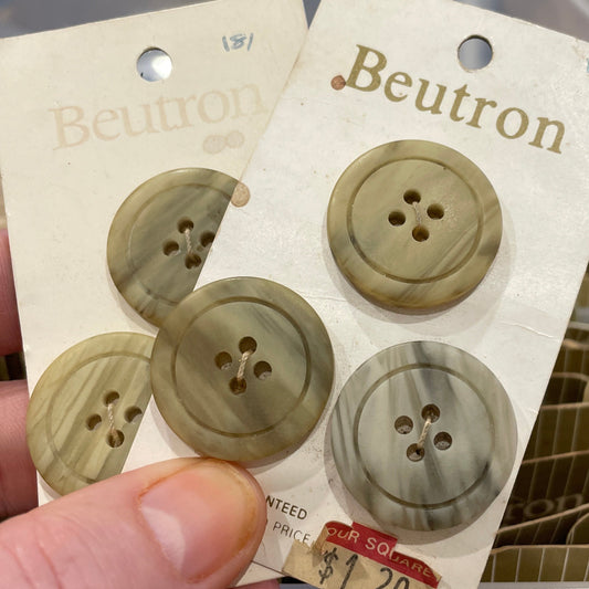 Beutron buttons on a card held by a hand with a blurred background