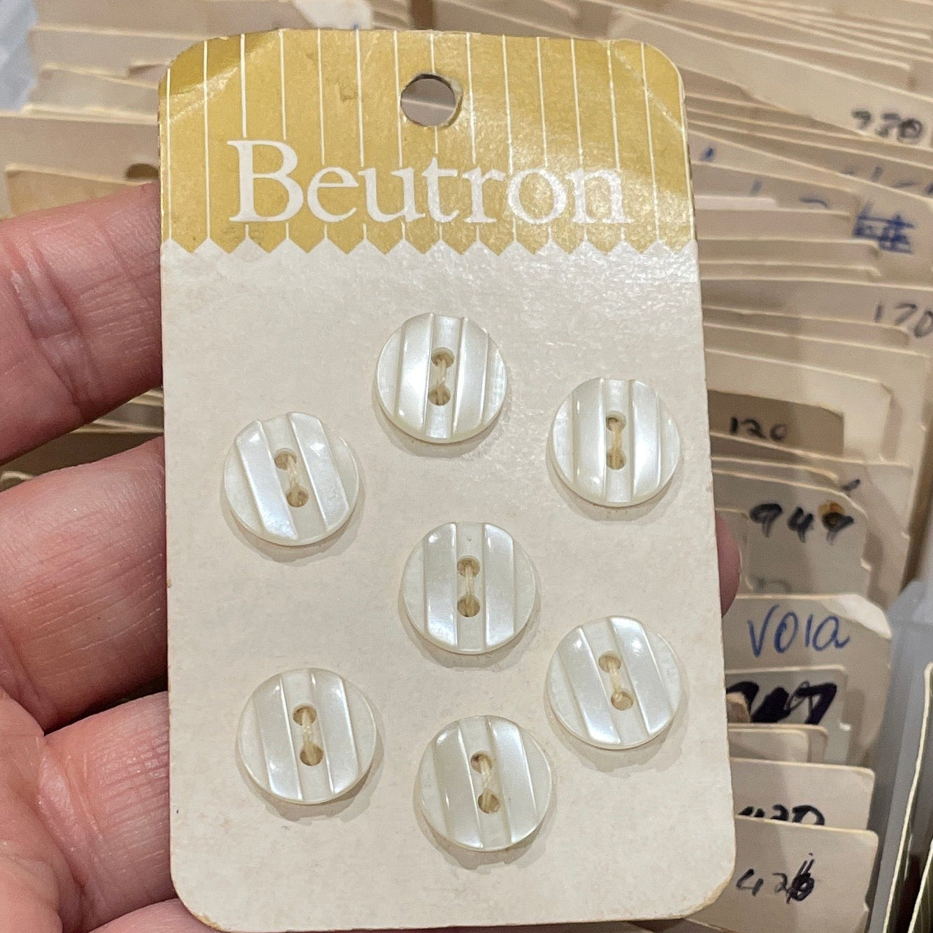 Hand holding a card with buttons, surrounded by more cards and containers.