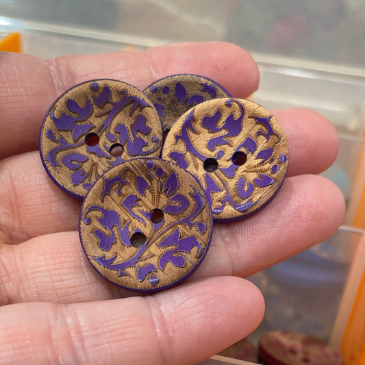 Hand holding decorative buttons with a container of buttons in the background