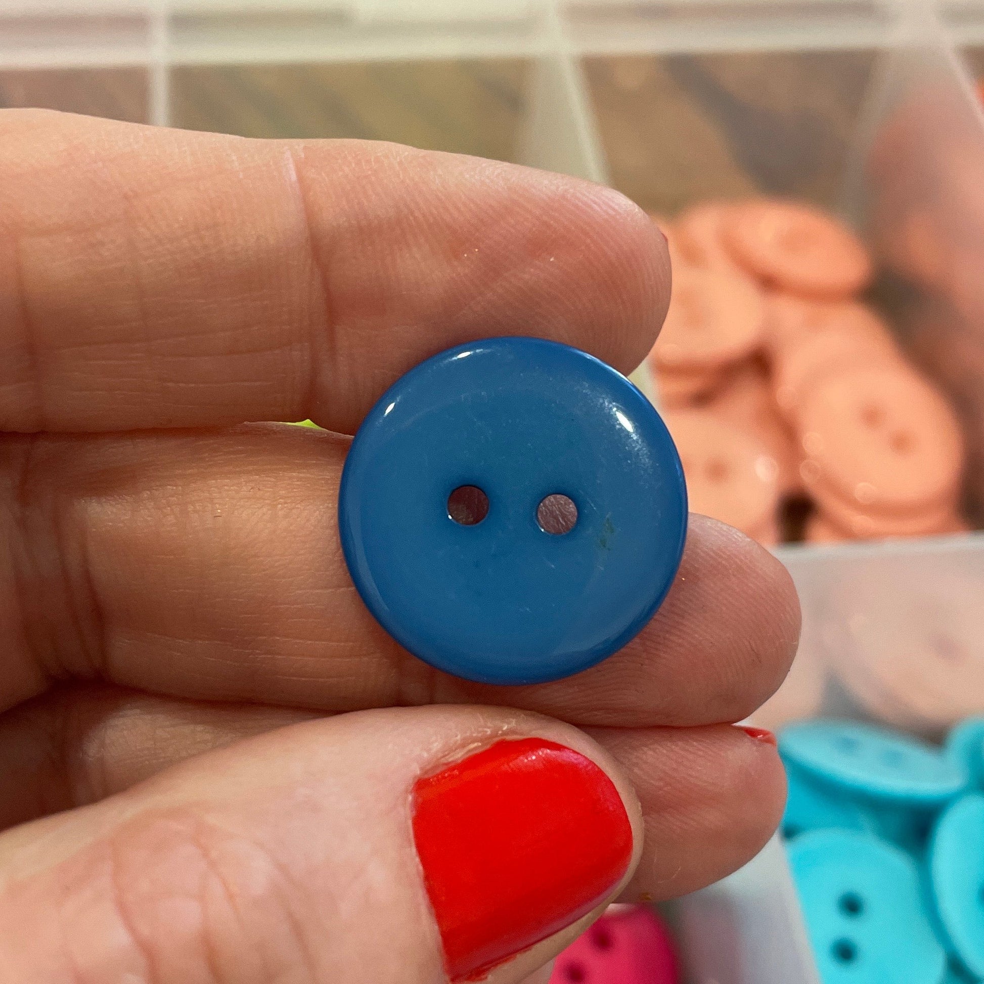 Hand holding a blue button with colorful buttons in the background