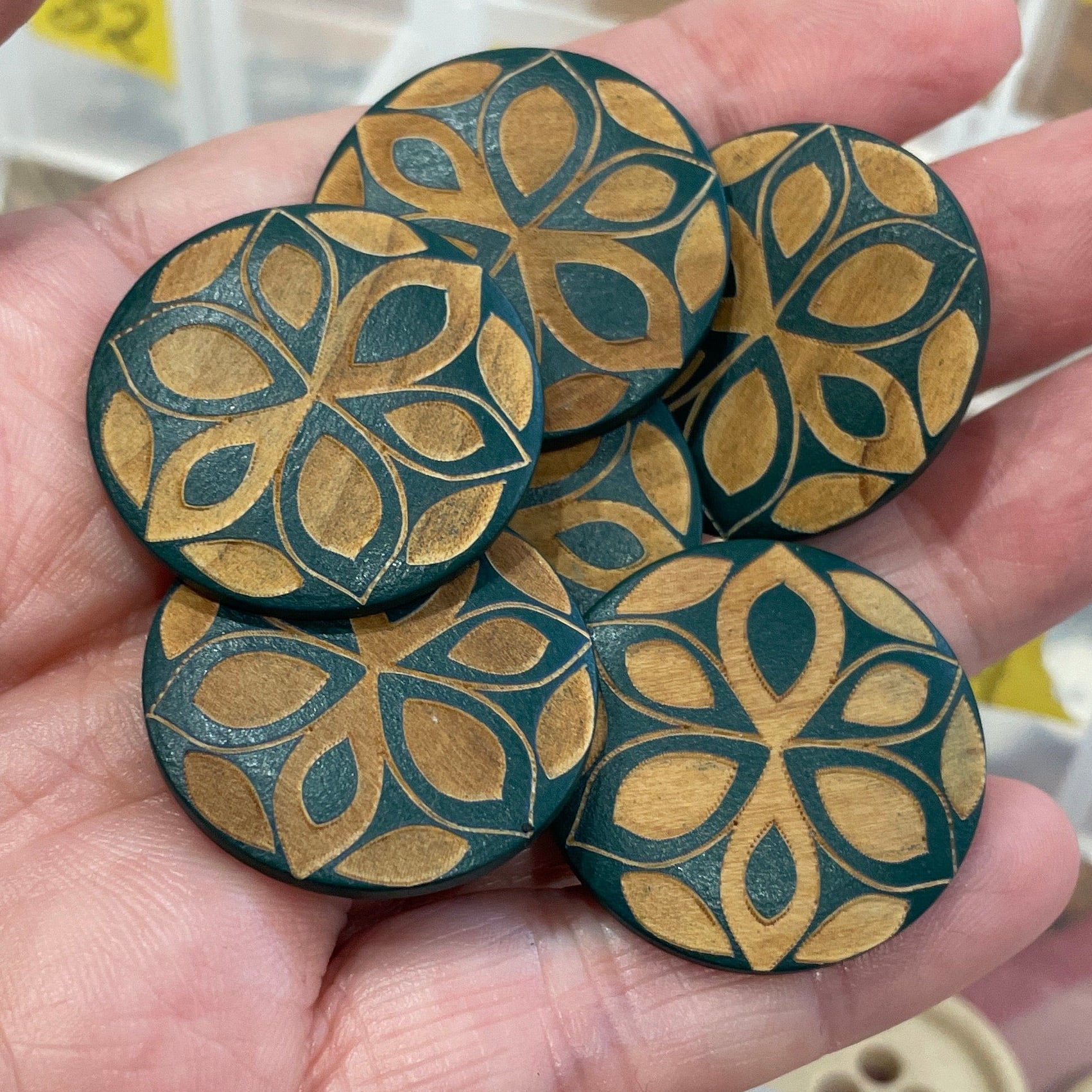 Hand holding decorative buttons with a patterned background