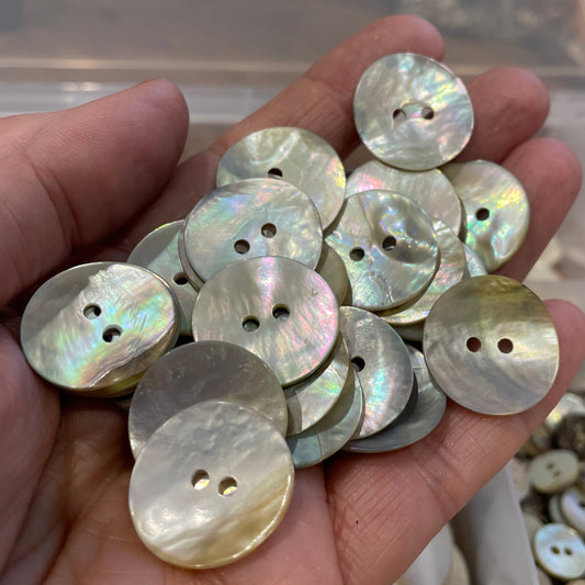 Hand holding a collection of round, multicolored buttons with a blurred background.