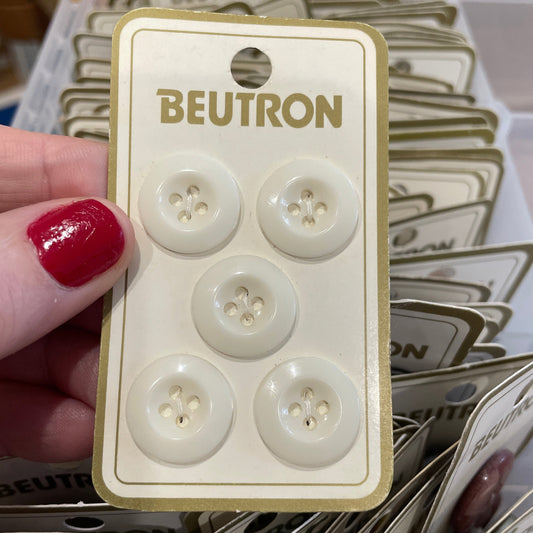 Beutron button packaging held by a hand with red nail polish, surrounded by more button packages.